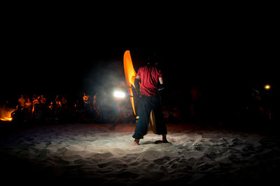 Rear view of man standing at illuminated night