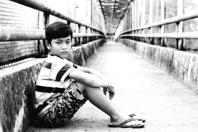 Portrait of boy sitting on bridge