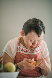 Elderly woman with down syndrome finds joy and independence in peeling mandarin