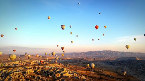 Hot air balloons over landscape against blue sky