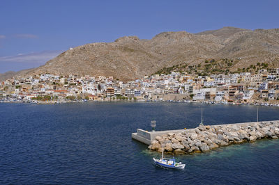 Sailboats in sea by town against sky