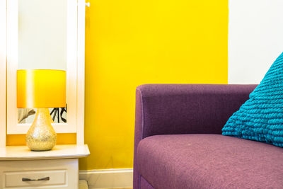 Close-up of sofa against yellow wall at home