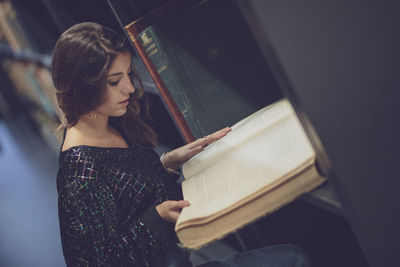 High angle view of young woman reading book at library