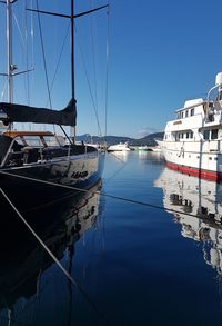 Sailboats moored on sea against clear blue sky