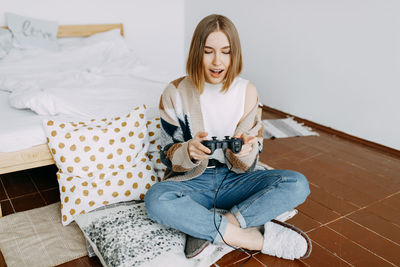 Full length of woman sitting on sofa at home