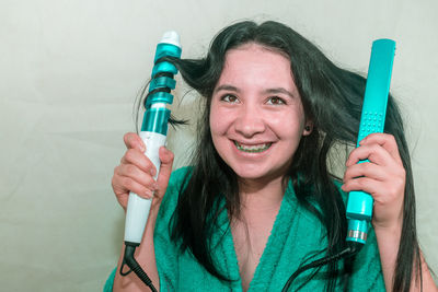 Close-up of young woman holding curling tongs and hair straightener