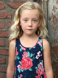 Portrait of cute girl standing against brick wall