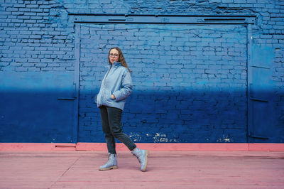 Portrait of young woman standing against wall