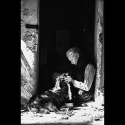 Woman sitting on cat looking at camera