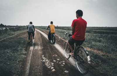 Rear view of people riding bicycle on road