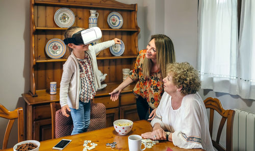 Girl with mother and grandmother wearing virtual reality simulator at home