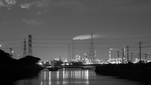 Illuminated bridge over river against sky at night