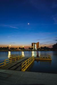 Illuminated bridge over river against sky at night