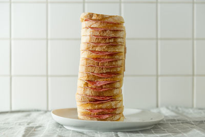 Close-up of bread stack with salami in plate on table