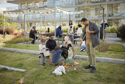 Neighbors relaxing and raking leaves in communal outdoor area