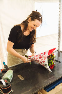 Happy female worker making bouquet at market stall