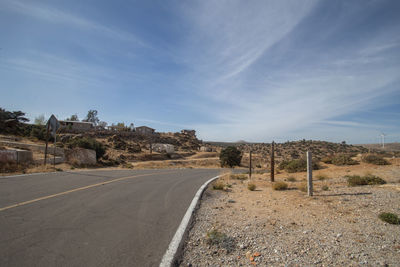 Empty road along landscape against sky