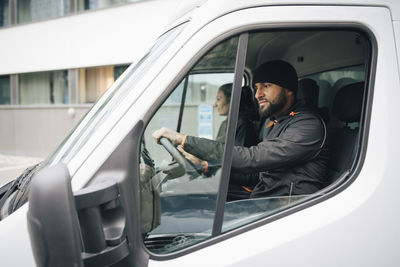 Male and female workers sitting in delivery van at city