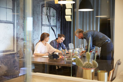 Creative business discussing in board room seen through glass