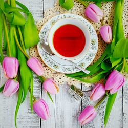 High angle view of tea cup with pink tulips on table