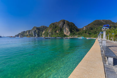 Scenic view of sea and mountains against clear blue sky