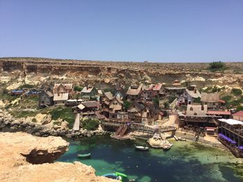 Houses by river and buildings against clear blue sky