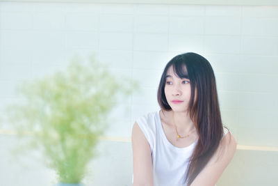 Portrait of young woman standing against wall