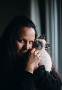 Adult woman with siamese kitten on her shoulder.