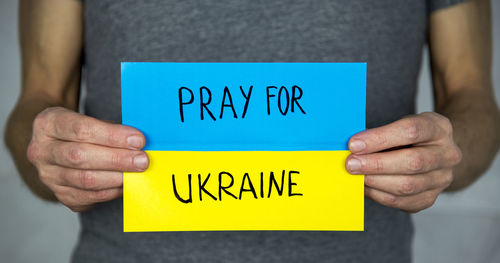 Man with pray for ukraine text on ukrainian flag 
