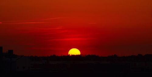 Silhouette buildings against orange sky