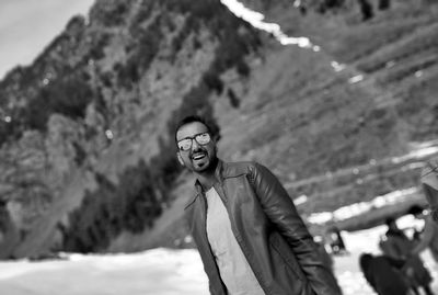 Tilt portrait of happy man standing against mountain during winter