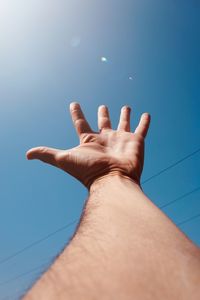 Close-up of hand against blue sky