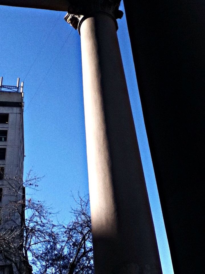 low angle view, blue, clear sky, built structure, architecture, building exterior, sunlight, copy space, outdoors, no people, day, architectural column, part of, sky, column, pole, building, lighting equipment, cropped, tree