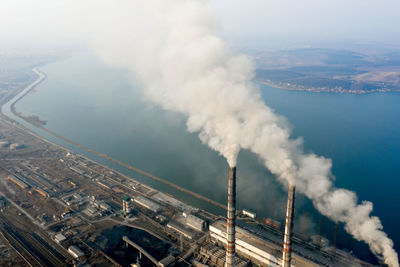 High angle view of smoke emitting from factory against sky