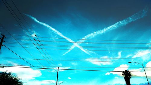 Low angle view of electricity pylon against blue sky