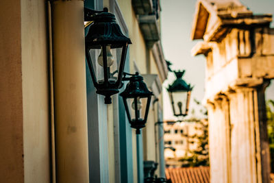 Low angle view of lamp hanging on street light against building