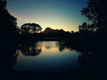 Silhouette trees by lake against sky during sunset