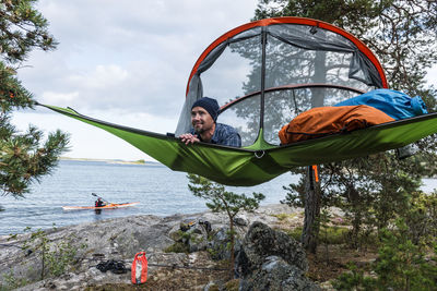 Man resting in hammock at lakeshore