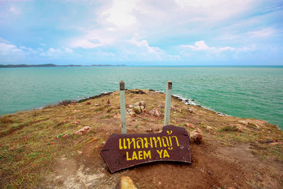 Information sign on beach against sky