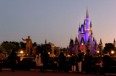 Group of people in front of illuminated buildings in city