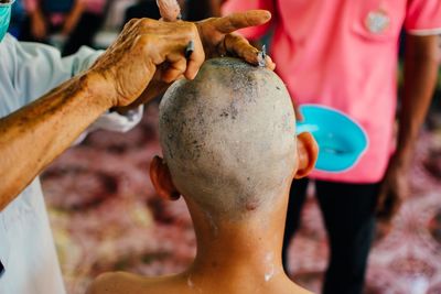 Close-up of barber shaving head of customer at salon