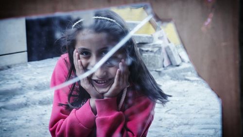 Smiling girl reflecting on broken glass