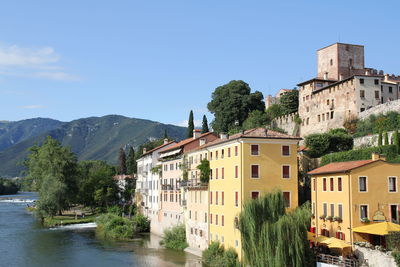 Houses by river and buildings against sky