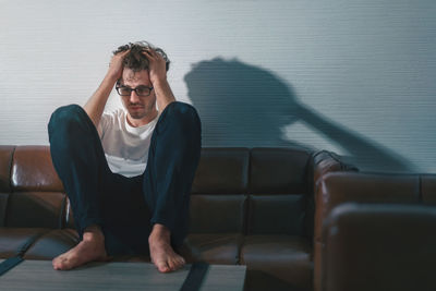 Young man sitting on sofa at home