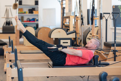 Male fitness pilates trainer shows exercises on special simulators. pilates stretch tables