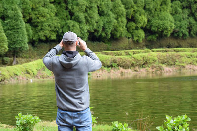 Man standing by lake against trees