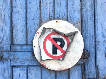 Torn no parking sign poster on blue weathered wooden door
