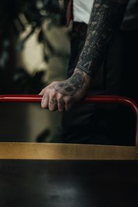 Cropped tattooed hand of man holding railing