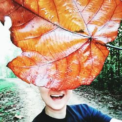 Portrait of young woman holding leaf