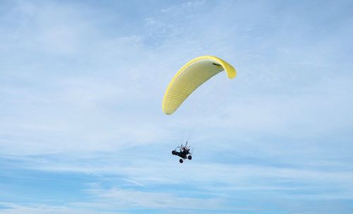 Low angle view of person paragliding against sky